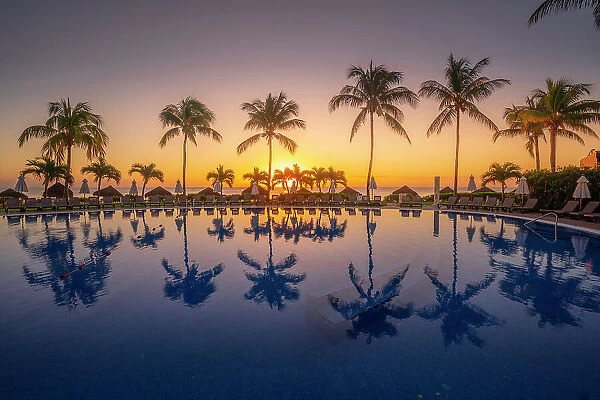 View of sunrise and palm tree reflections in hotel pool near Puerto Morelos, Caribbean Coast, Yucatan Peninsula, Mexico, North America