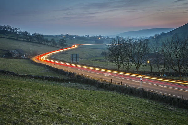 View of vehicle trail lights on A623 at Sparrowpit at dusk, Peak District National Park