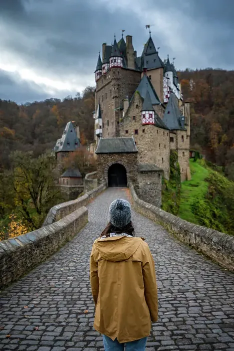 Framed Print : Back view of young woman with yellow jacket looking at Eltz medieval historic castle in an autumn landscape with trees at sunrise, Wierschem, Rhineland-Palatinate, Germany, Europe Framed Print : Back view of young woman with yellow jacket looking at Eltz medieval historic castle in an autumn landscape with trees at sunrise, Wierschem, Rhineland-Palatinate, Germany, Europe