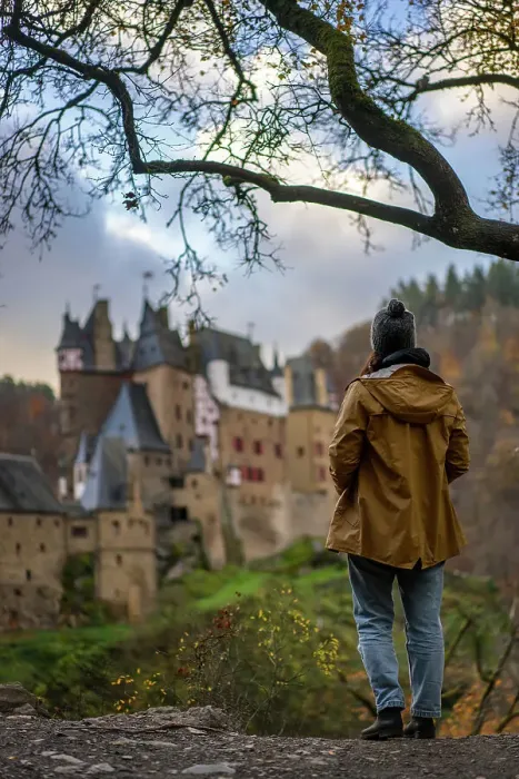 Framed Print : Back view of young woman with yellow jacket looking at Eltz medieval historic castle in an autumn landscape with trees at sunrise, Wierschem, Rhineland-Palatinate, Germany, Europe Framed Print : Back view of young woman with yellow jacket looking at Eltz medieval historic castle in an autumn landscape with trees at sunrise, Wierschem, Rhineland-Palatinate, Germany, Europe