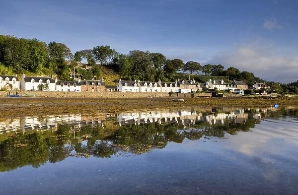 Village of Plockton bathed in early morning light and reflecting in calm sea at low tide