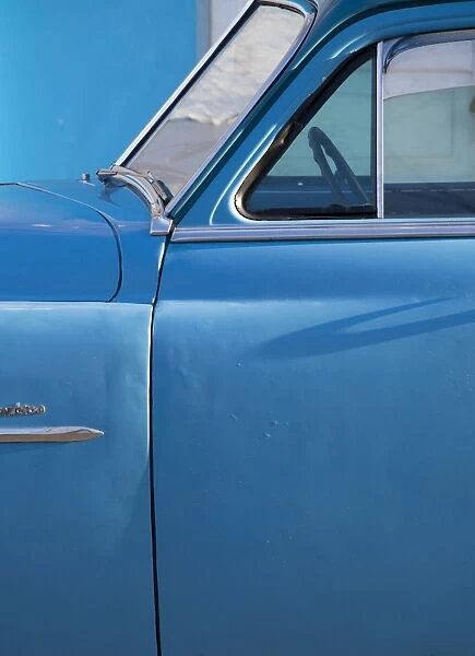 Detail of vintage blue American car against painted blue wall, Cienfuegos, Cuba, West Indies, Central America