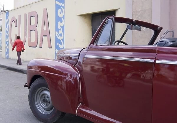 A vintage car near a Viva Cuba sign painted on a wall in cental Havana