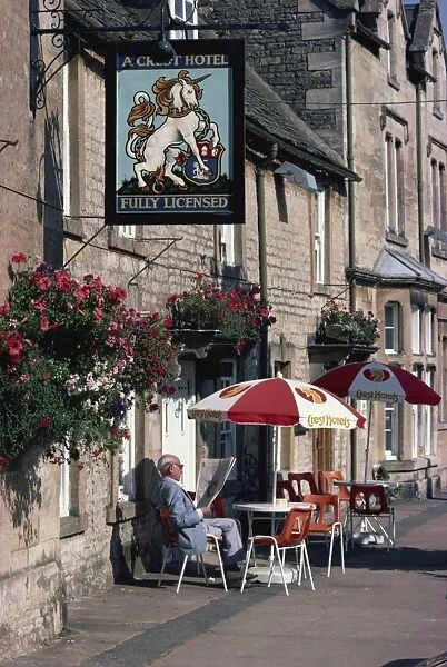 Visitor relaxes outside a typical pub, Stow-on-the-Wold, Gloucestershire