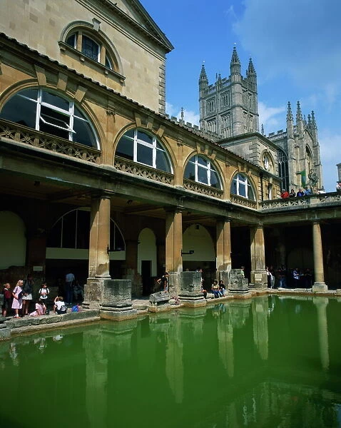 Visitors in the Roman Baths, with the Abbey beyond in Bath, UNESCO World Heritage Site