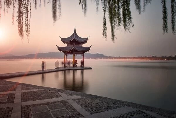 Visitors are taking the last shots with a pagoda at West Lake as the sun is sinking, Hangzhou, Zhejiang, China, Asia