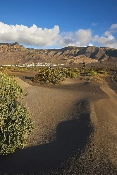 Volcanic cliffs rising to 600m over desert landscape near Famara, with its low-rise bungalow development, in the north west of the island, Famara, Lanzarote, Canary Islands, Spain, Atlantic