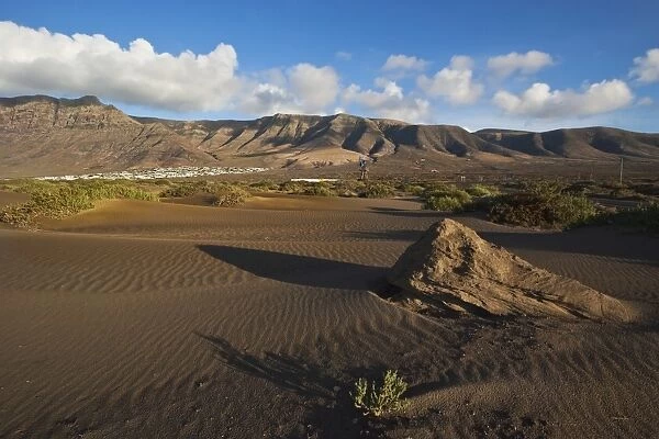 Volcanic cliffs rising to 600m over desert landscape near Famara, with its low-rise bungalow development, Famara, Lanzarote, Canary Islands, Spain, Atlantic