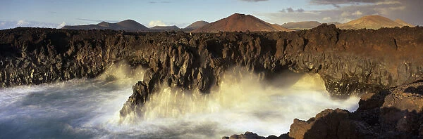 Volcanic coastline with waves crashing into sea caves, Los Hervideros