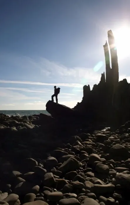 Framed Print : A walker stands on a boulder beside the isolated Bear Rock, a Culm pinnacle near Hartland Quay