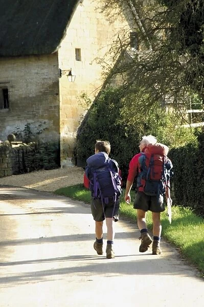 Two walkers with rucksacks on the Cotswold Way footpath, Stanton village