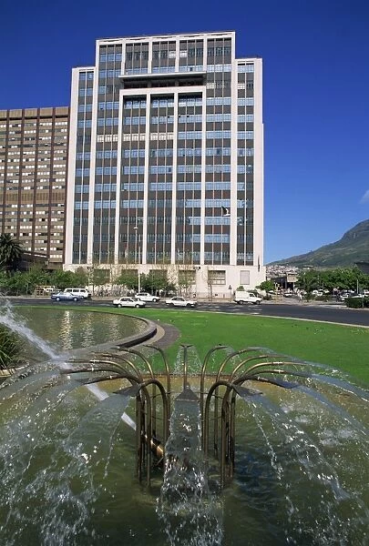 Water fountain on round-a-bout with an office building behind