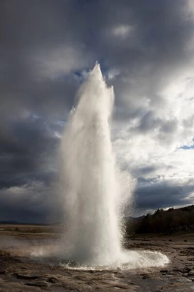 Water spout from Strokkur Geysir exploding into the sky on a stormy evening