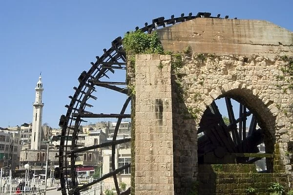 Water wheel on the Orontes River and minaret behind