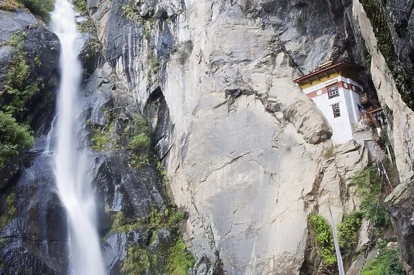 A waterfall flowing past a temple built into the side of a cliff, Tigers Nest