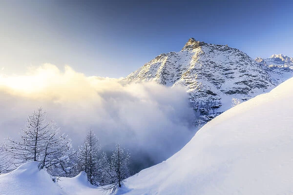 Wave of clouds illuminated by sunset in winter, Valmalenco, Valtellina, Lombardy, Italy