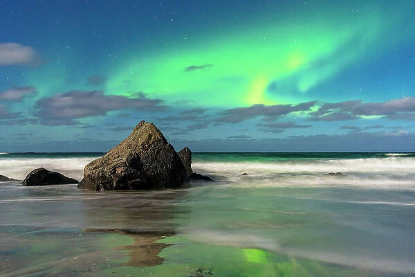 Waves crashing on rocks under a bright sky with te Aurora Borealis (Northern Lights), Skagsanden beach, Ramberg, Lofoten Islands, Nordland, Norway, Scandinavia, Europe