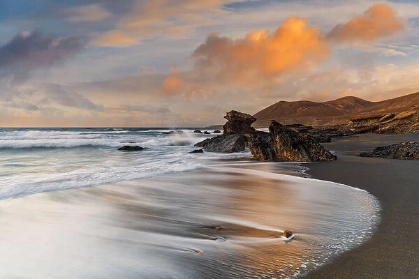Waves crashing on sandy beach Playa de la Solapa at sunset, Fuerteventura, Canary Islands