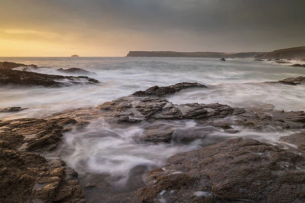 Waves swirl over rocky ledges at sunset on the North Cornwall coast, Cornwall, England