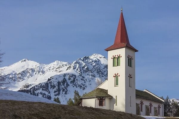 The white alpine church framed by snowy peaks, Maloja, Bregaglia Valley, Canton of Graubunden
