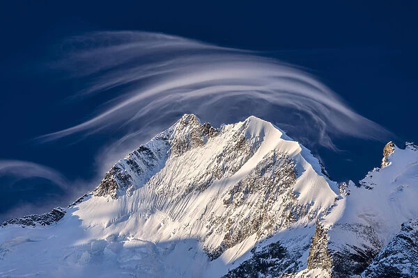 White cloud at dawn lights up Piz Bernina and Biancograt, Engadine, Canton of Graubunden
