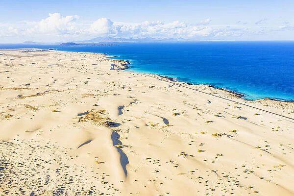 White sand dunes meeting the blue Atlantic Ocean, aerial view, Corralejo Nature Park