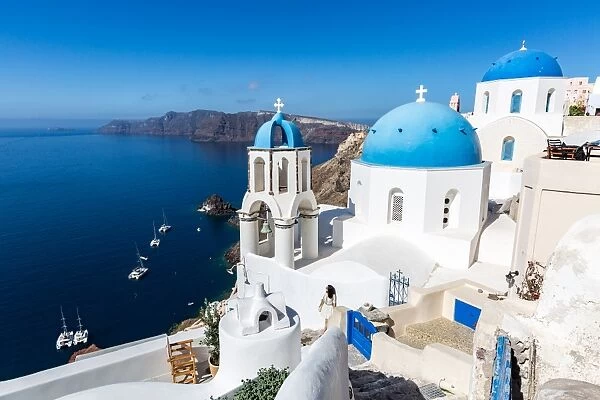 White washed stone buildings and the blue cupolas of a church in Oia, Santorini, Cyclades