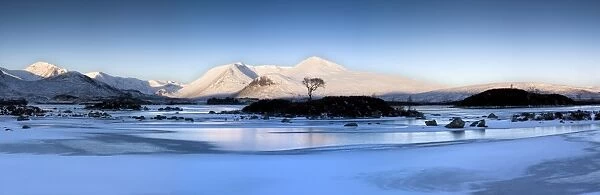 Winter view at dawn over frozen Lochain Na h Achlaise to sun-kissed Black Mount hills