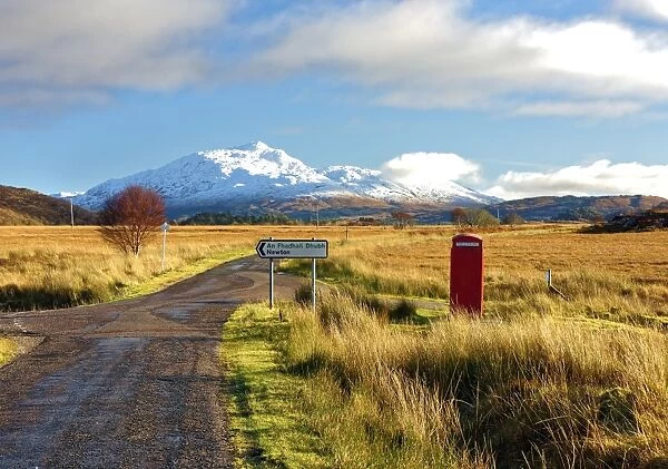 Winter view of a red telephone box and road toward snow covered Beinn Resipol mountain