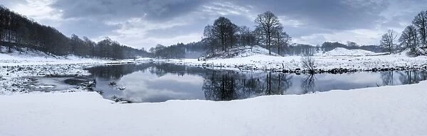 Winter view of River Brathay at dawn, under snow with reflections, near Elterwater Village
