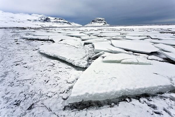 Winter view over slabs of broken lake ice covered in snow towards Kirkjufell (Church Mountain), near Grundarfjordur, Snaefellsnes Peninsula, Iceland, Polar Regions