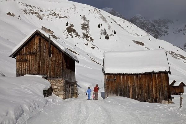 Winter walk on snowy path through wooden barns around San Pellegrino Pass