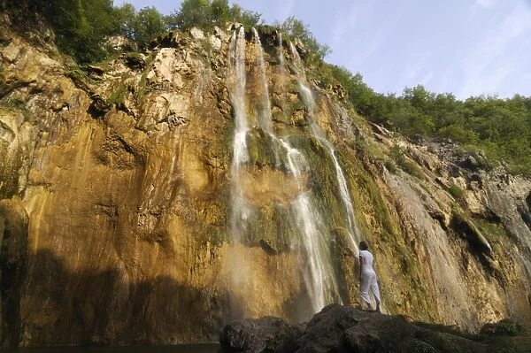Woman admiring the giant waterfall in the Plitvice Lakes National Park