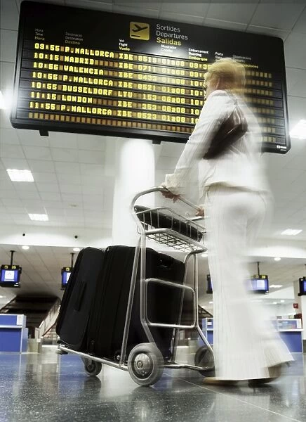 Woman with baggage trolley in departures, Ibiza Airport, Spain, Europe