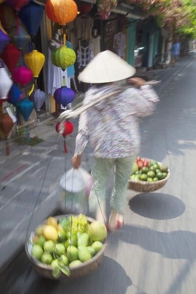 Woman carrying fruit along street, Hoi An, Quang Nam, Vietnam, Indochina, Southeast Asia, Asia