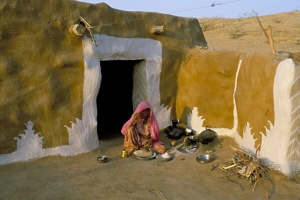 Woman cooking outside house with painted walls