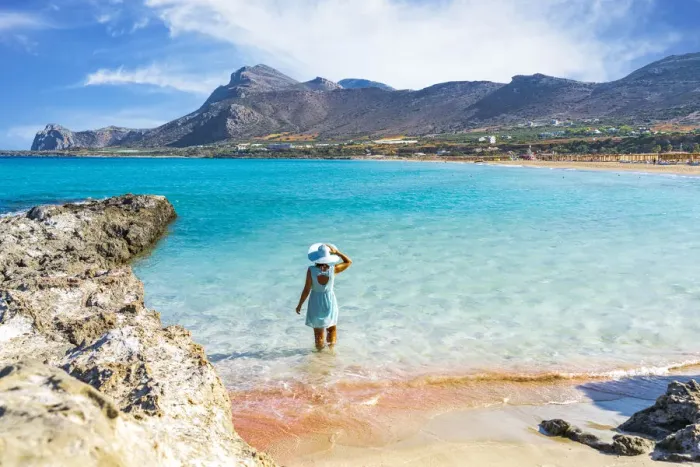 Framed Print : Woman in dress standing in the turquoise clear sea facing the pink sand beach of Framed Print : Woman in dress standing in the turquoise clear sea facing the pink sand beach of
