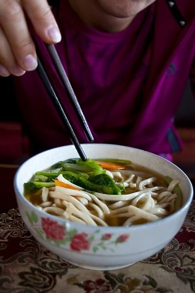 Woman eating noodle soup, Lhasa, Tibet, China, Asia