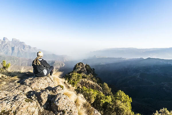 Woman enjoying the early morning sun on the cliffs, Simien Mountains National Park