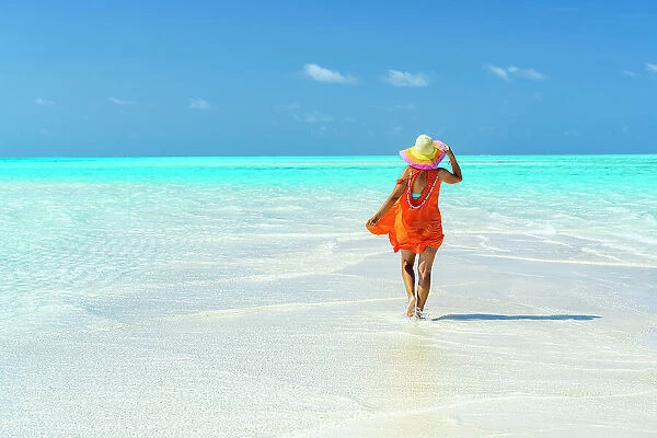 Woman with hat walking to the crystal clear sea, Zanzibar, Tanzania, East Africa, Africa