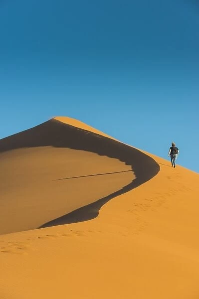 Woman hiking up the giant Sand Dune 45, Sossusvlei, Namib-Naukluft National Park