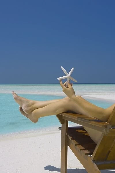 Woman holding seastar on the beach, Maldives, Indian Ocean, Asia