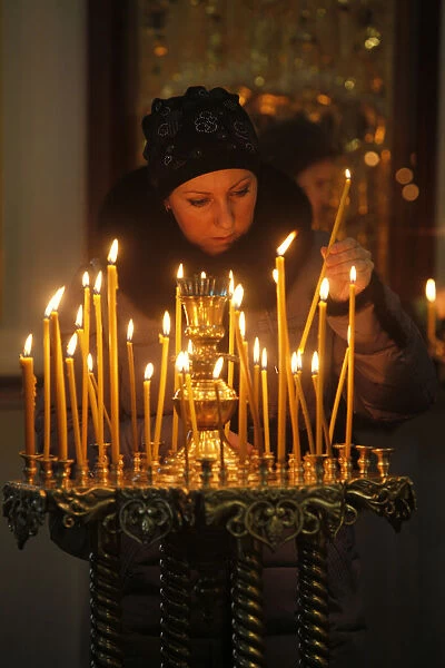 Woman lighting a candle, Trinity Cathedral, St. Petersburg, Russia, Europe