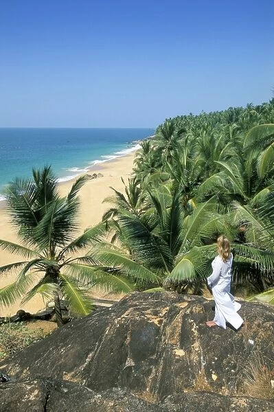 Woman looking over coconut palms to the beach