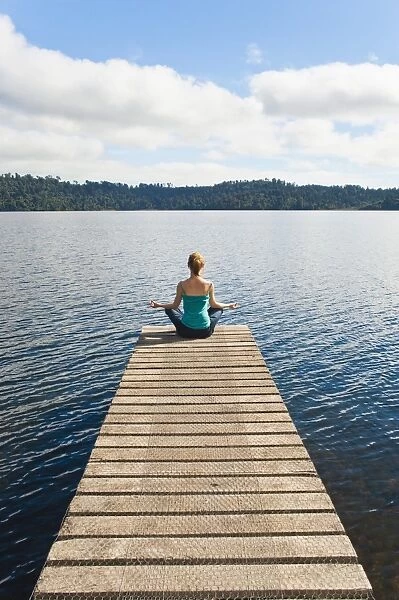 Woman meditating on a jetty, Lake Ianthe, West Coast, South Island, New Zealand, Pacific
