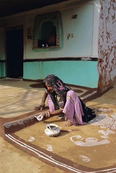 Woman painting the wall of a village house