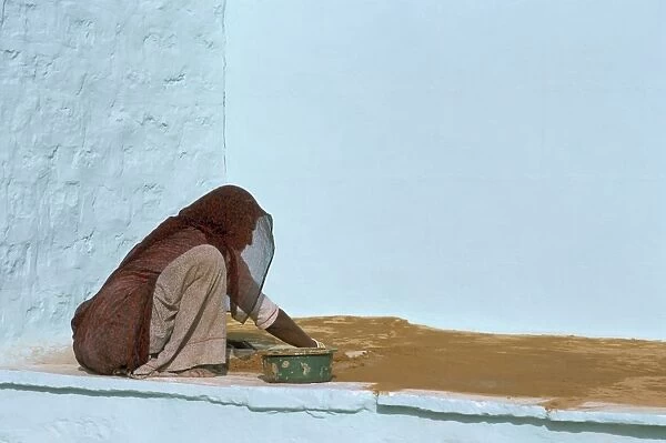 Woman painting walls in a village in the Barmer area