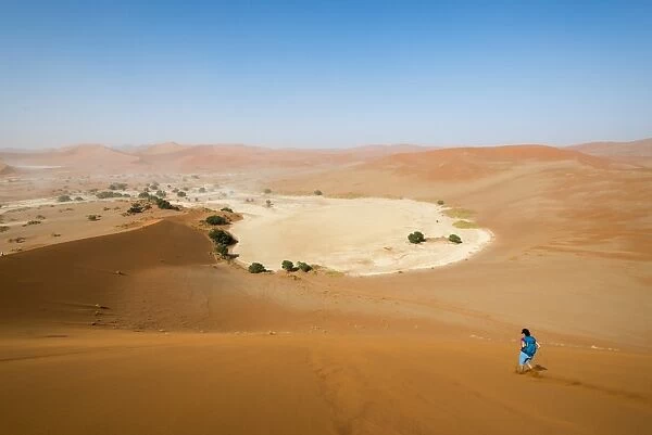 A woman runs down from the summit of Sossusvlei sand dune, Namibia, Africa