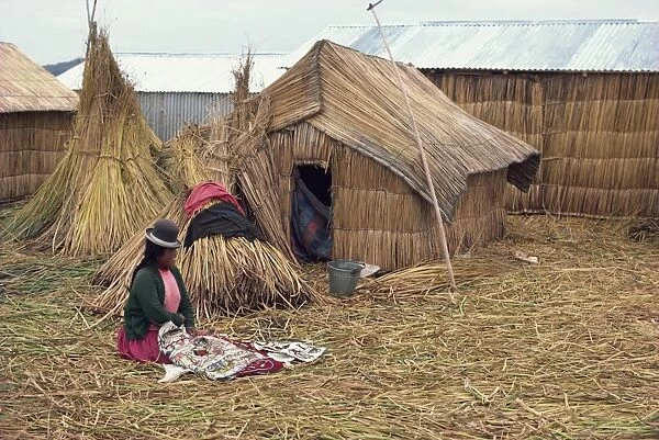 A woman with her sewing sitting outside her reed house