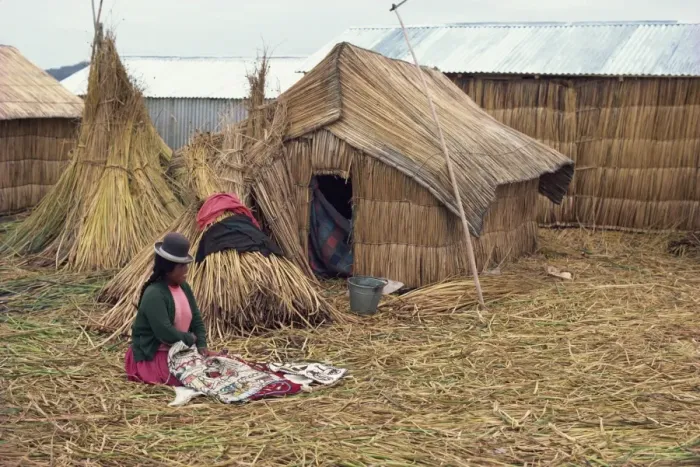 Framed Print : A woman with her sewing sitting outside her reed house